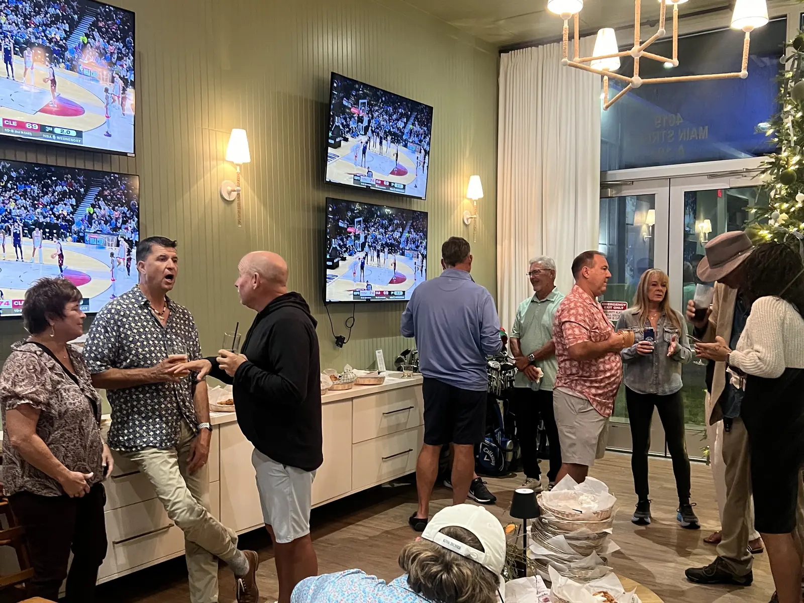 A crowd filling the lounge at Tee Off at The Wharf, drinks in hand with the TVs on